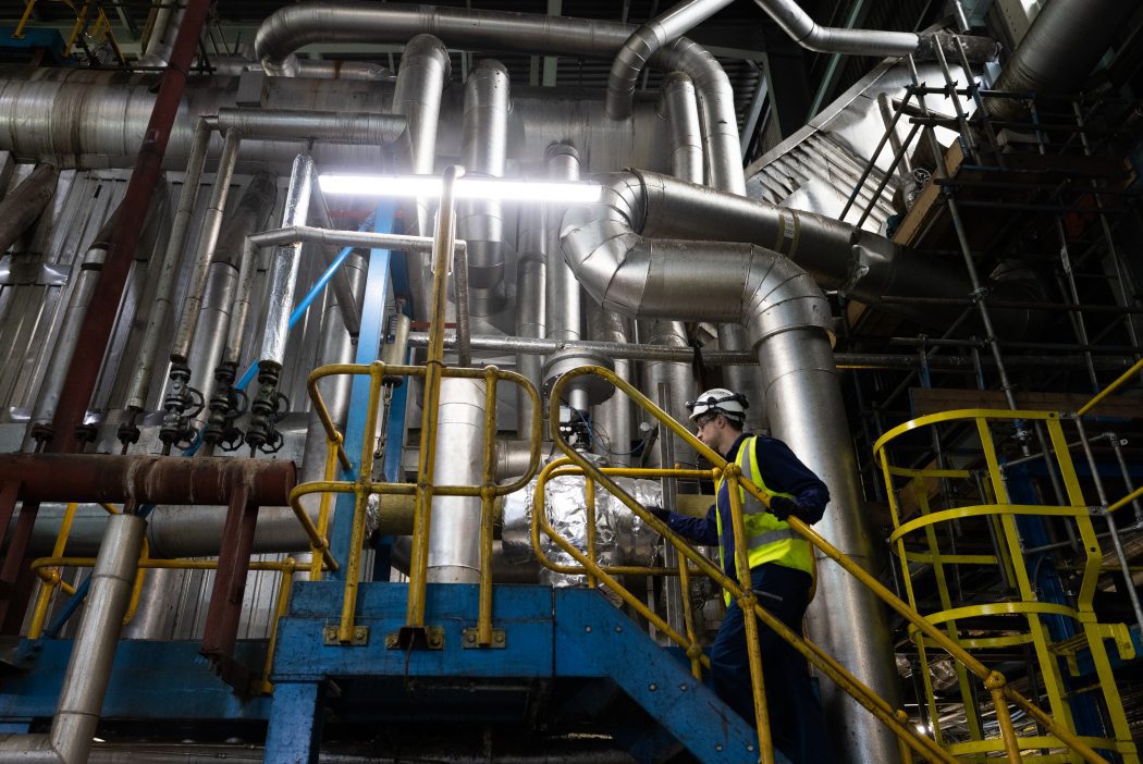 Man in high visibility jacket climbs stairs at a factory