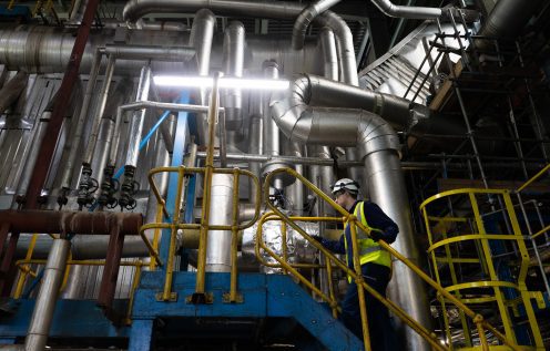 Man in high visibility jacket climbs stairs at a factory