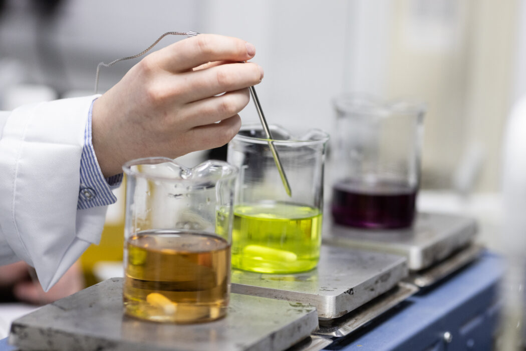 A hand is hovering over a scientific beaker