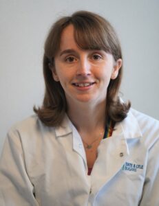 Picture of woman wearing white laboratory coat and smiling at camera