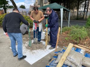 Team members use wooden sticks to break up lumps of soil