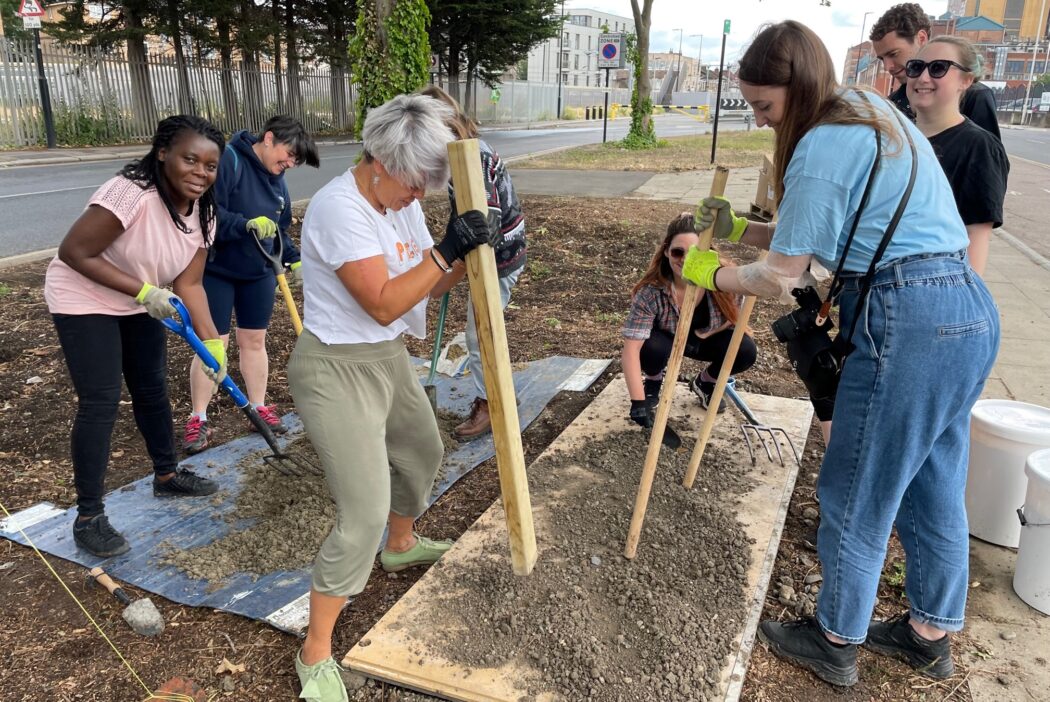 Team of volunteer bash mud and break soil in to small pieces