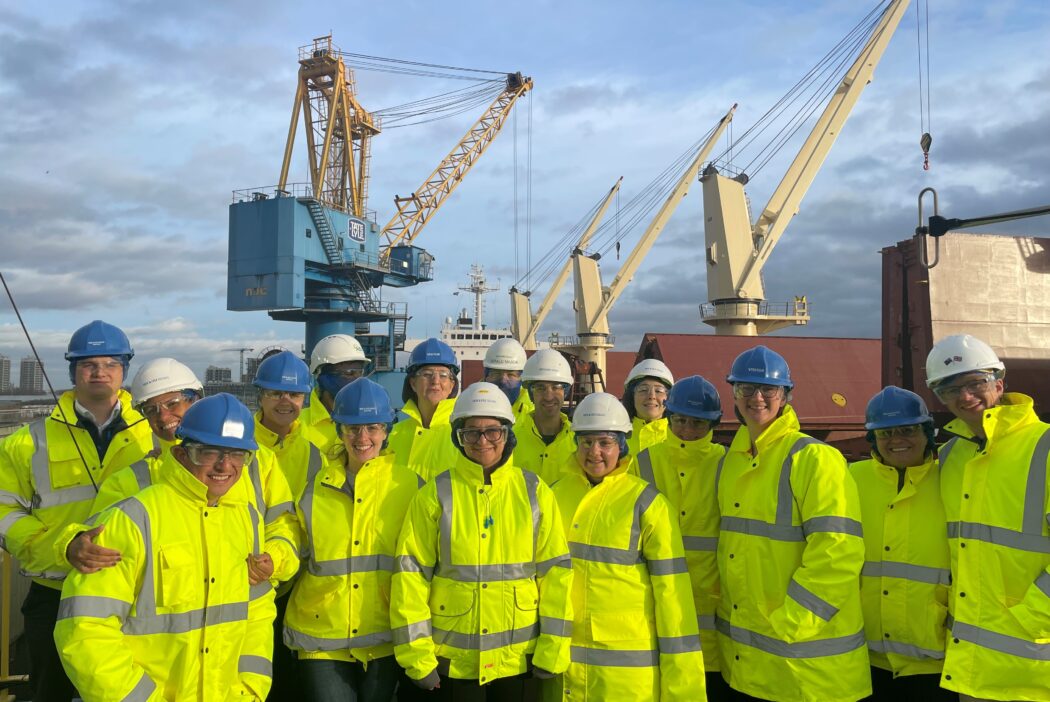 Group of people in hi-vis jackets standing next to a crane