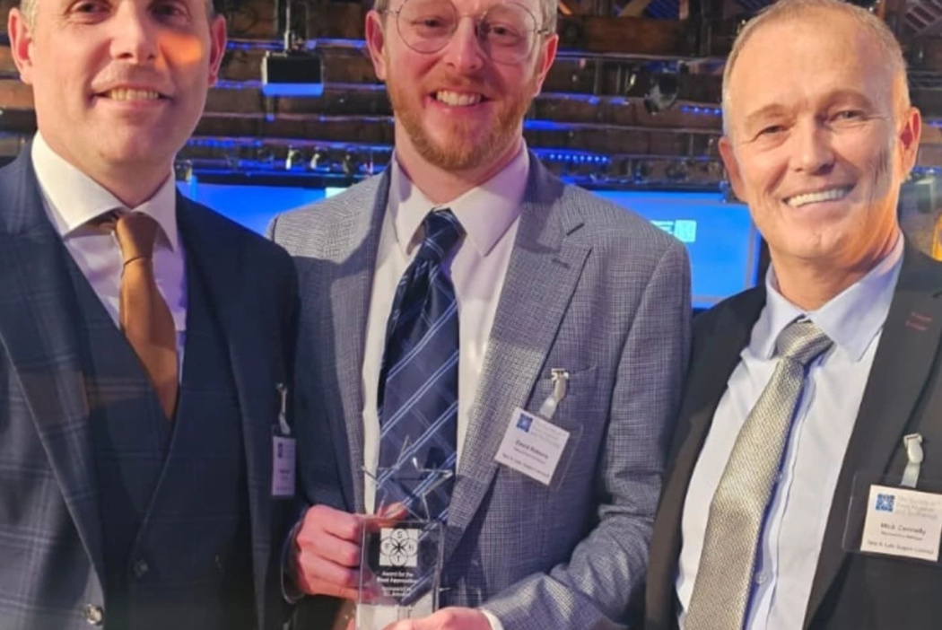 Man in suit stands with award