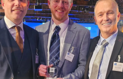 Man in suit stands with award