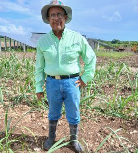 Sugarcane farmer, David Akierman, in a field in front of solar panels