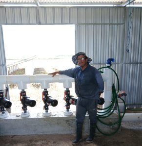 David stood in front of irrigation pumps in a metal pump house