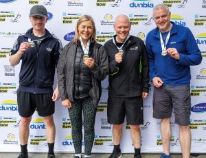 Four people stand holding medals around their necks